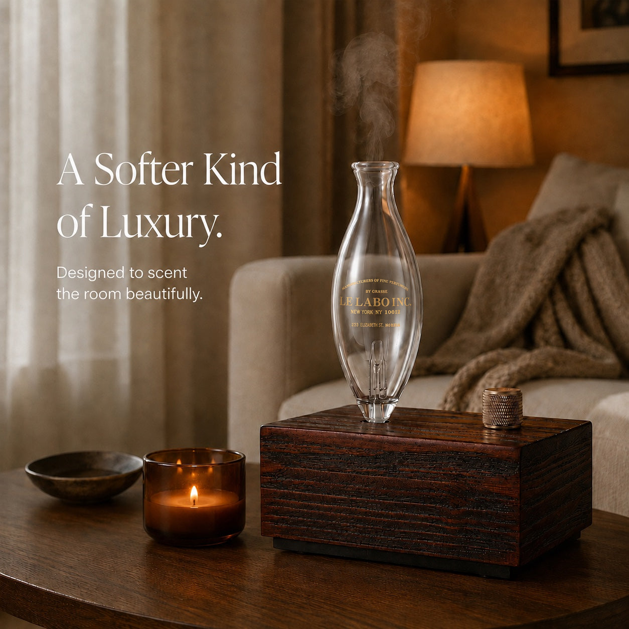 Wooden diffuser beside a candle and a linen sofa in a warmly lit room